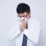 鼻炎で鼻をかむ男性