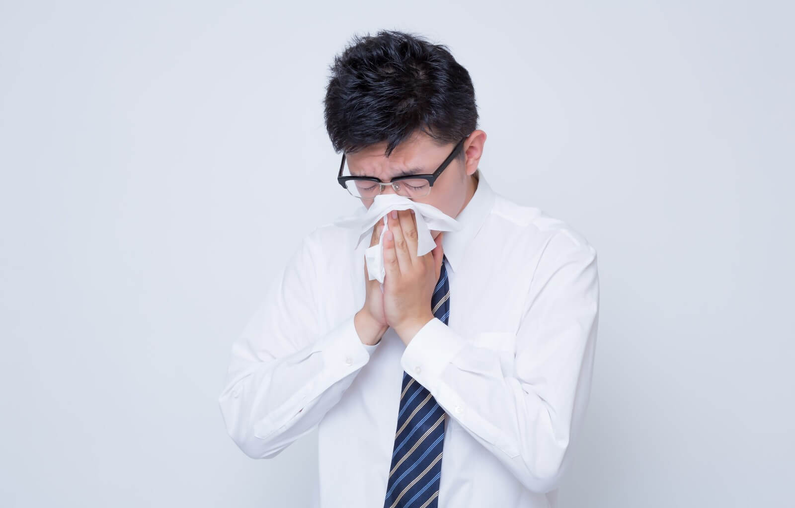 鼻炎で鼻をかむ男性